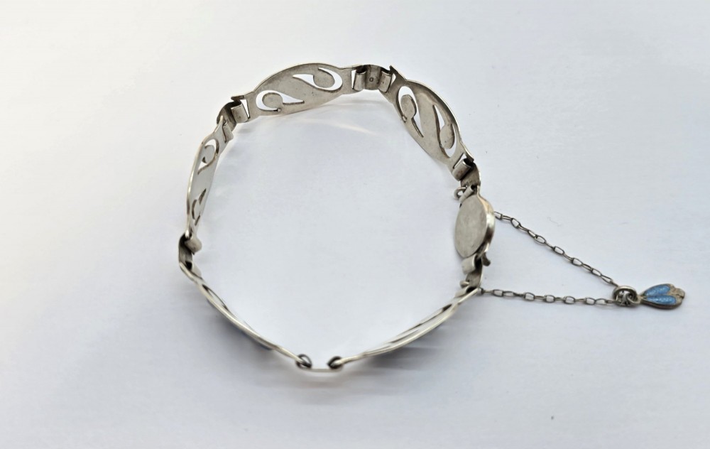 An Edwardian silver link bracelet featuring pierced oval panels filled with light blue enamel and connected by a safety chain. View VI