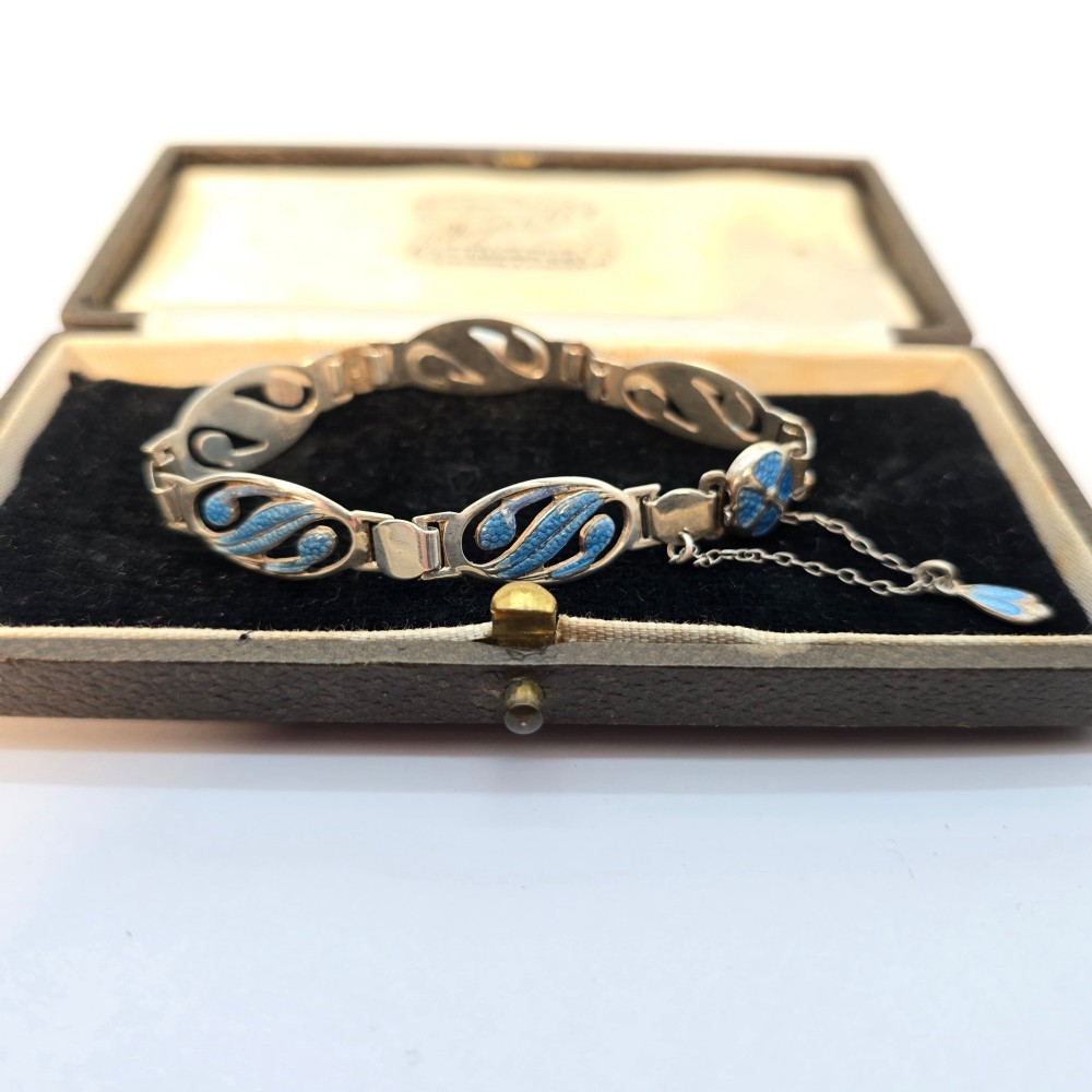 An Edwardian silver link bracelet featuring pierced oval panels filled with light blue enamel and connected by a safety chain. View VII