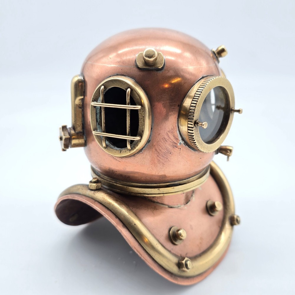 A miniature copper and brass deep-sea divers helmet featuring glass viewports, side valves, and brass shoulder plate studs on a plain white background.