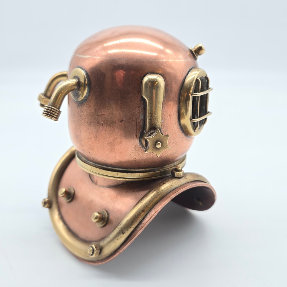 A miniature copper and brass deep-sea divers helmet featuring glass viewports, side valves, and brass shoulder plate studs on a plain white background. View IV