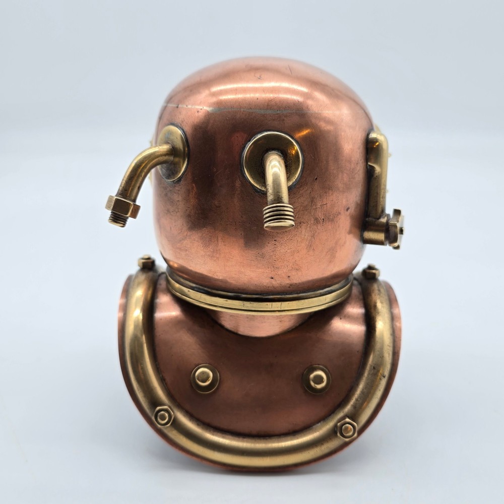 A miniature copper and brass deep-sea divers helmet featuring glass viewports, side valves, and brass shoulder plate studs on a plain white background. View V