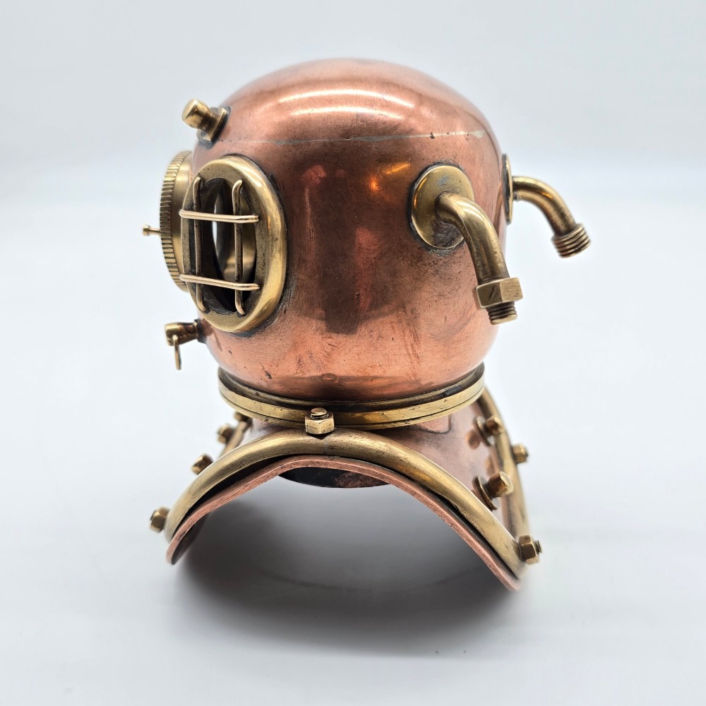 A miniature copper and brass deep-sea divers helmet featuring glass viewports, side valves, and brass shoulder plate studs on a plain white background. View VI