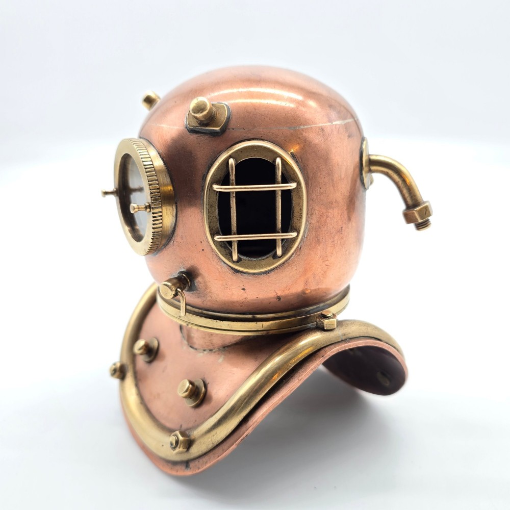 A miniature copper and brass deep-sea divers helmet featuring glass viewports, side valves, and brass shoulder plate studs on a plain white background. View VII