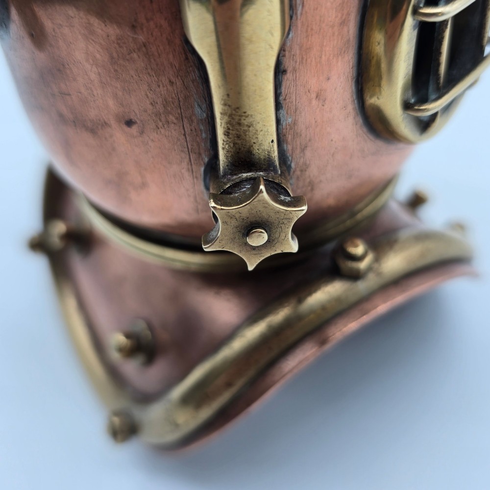 A miniature copper and brass deep-sea divers helmet featuring glass viewports, side valves, and brass shoulder plate studs on a plain white background. View XI