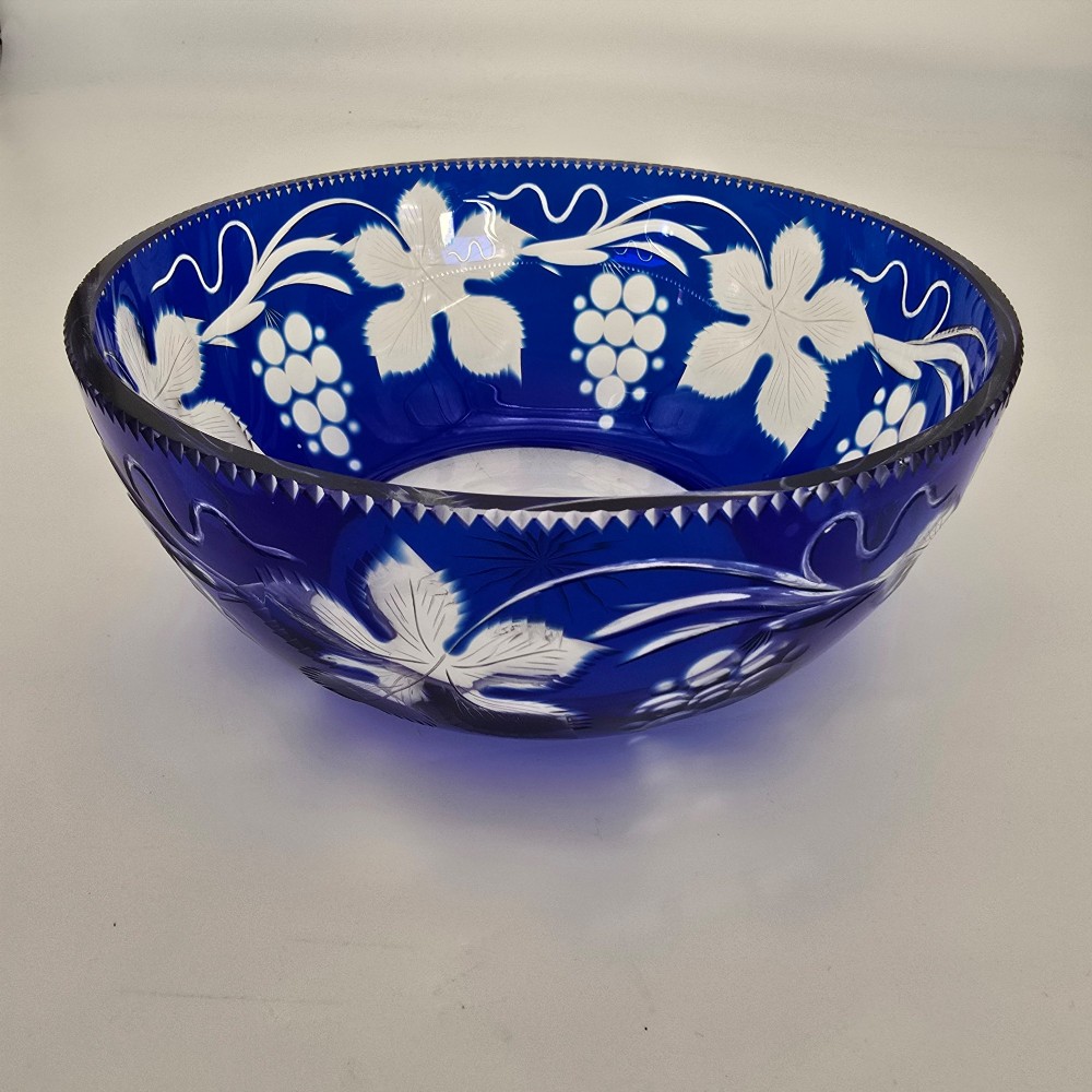 A large round Bohemian cobalt blue cut-to-clear glass bowl featuring etched grapevine leaves, grape clusters, and a serrated rim. View III