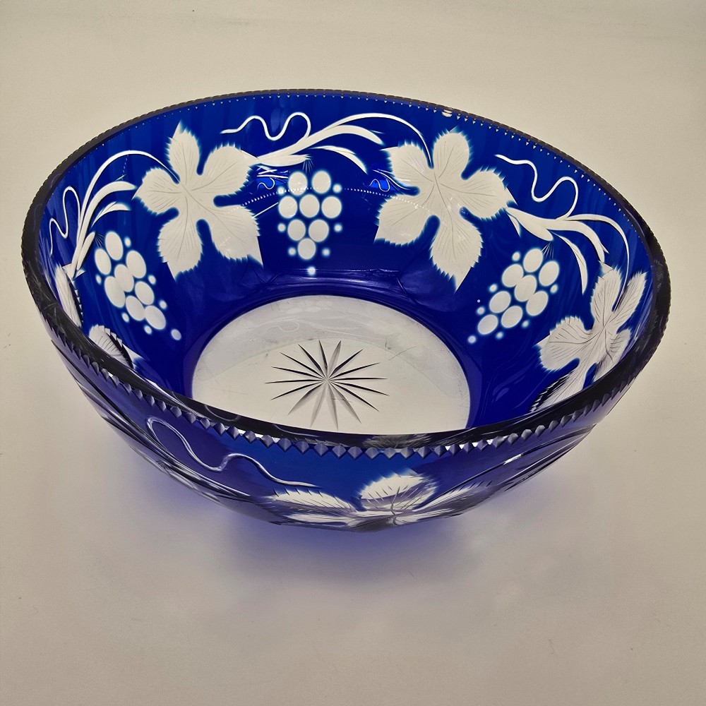A large round Bohemian cobalt blue cut-to-clear glass bowl featuring etched grapevine leaves, grape clusters, and a serrated rim. View VIII