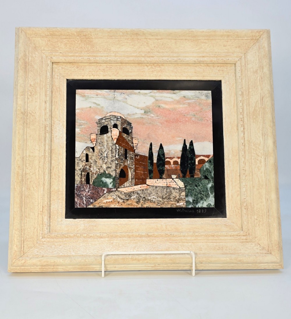 A framed Italian pietra dura panel depicting a stone building and cypress trees rendered in inlaid coloured marble.