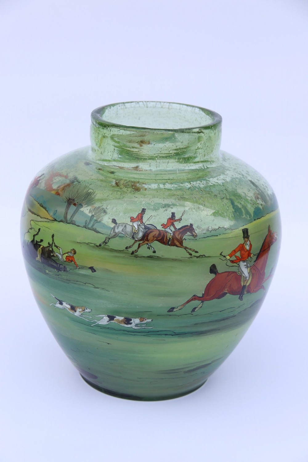 A bulbous green hand-blown glass vase featuring a hand-painted enamel scene of fox hunters riding horses across a landscape. View V