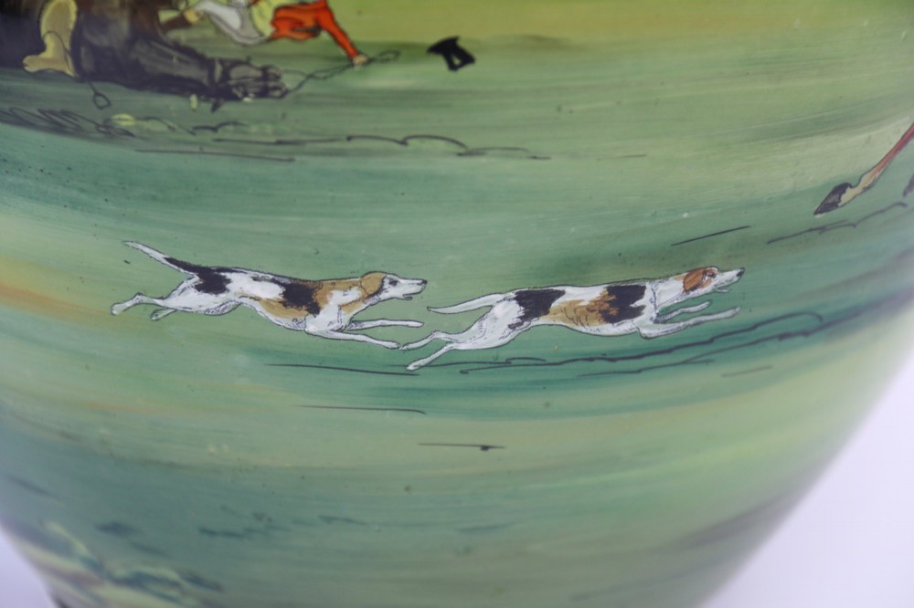 A bulbous green hand-blown glass vase featuring a hand-painted enamel scene of fox hunters riding horses across a landscape. View X