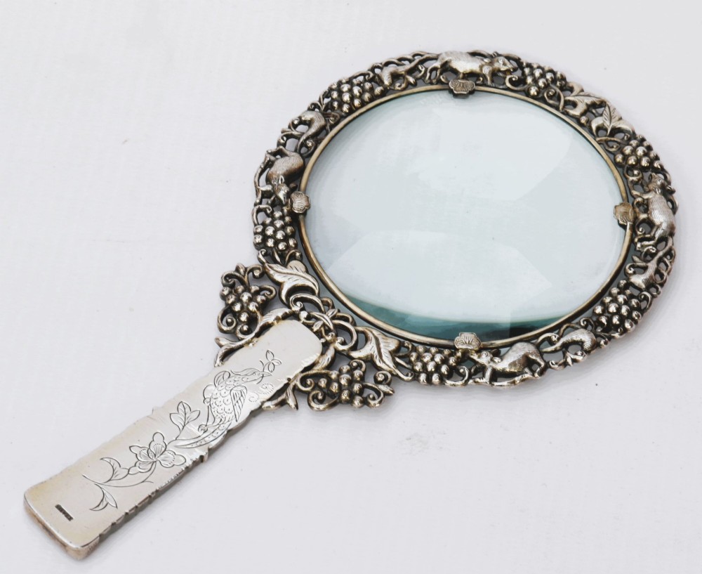 A late 19th-century Chinese silver magnifying glass featuring a carved white jade handle and an openwork grapevine frame with animal details. View II