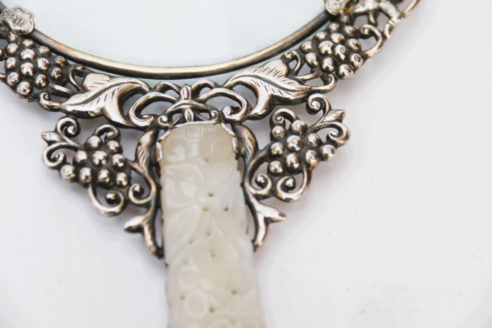 A late 19th-century Chinese silver magnifying glass featuring a carved white jade handle and an openwork grapevine frame with animal details. View VI