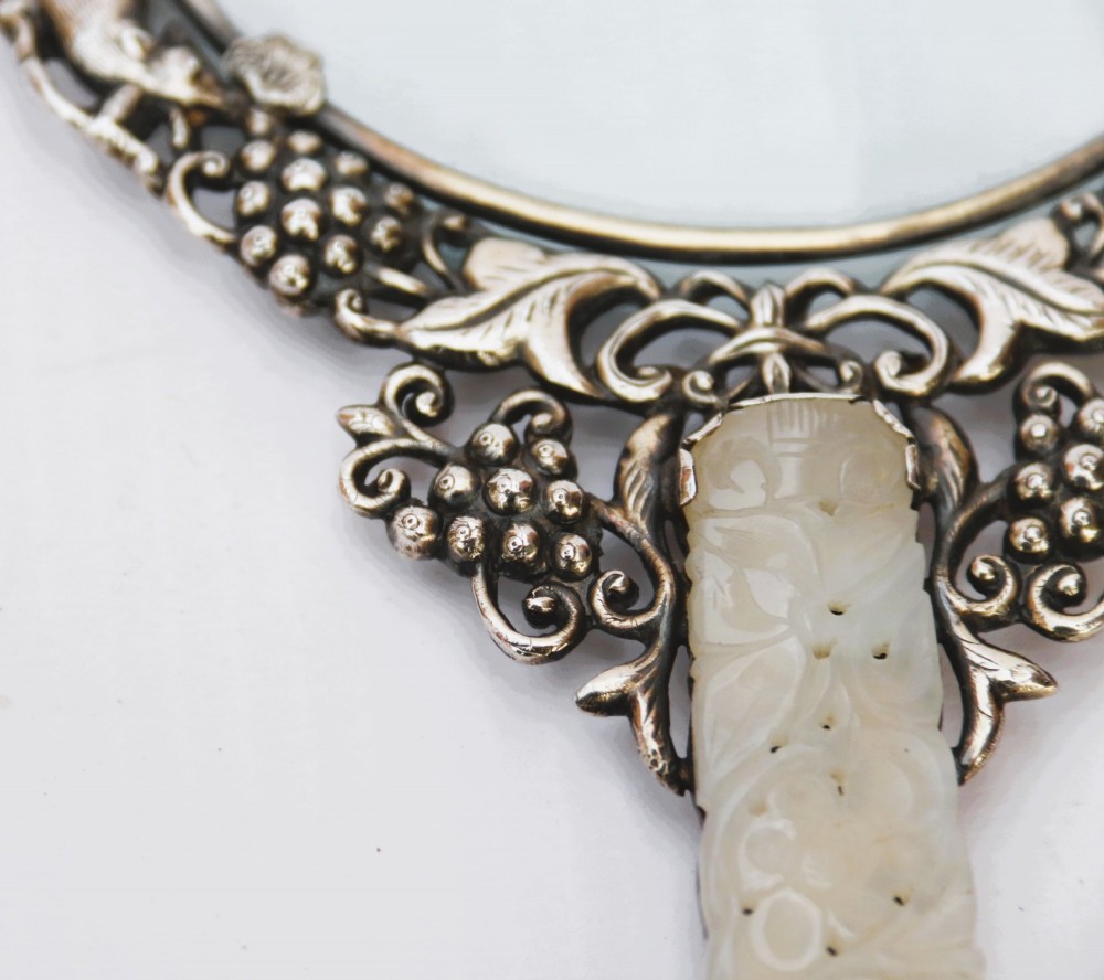 A late 19th-century Chinese silver magnifying glass featuring a carved white jade handle and an openwork grapevine frame with animal details. View XIV