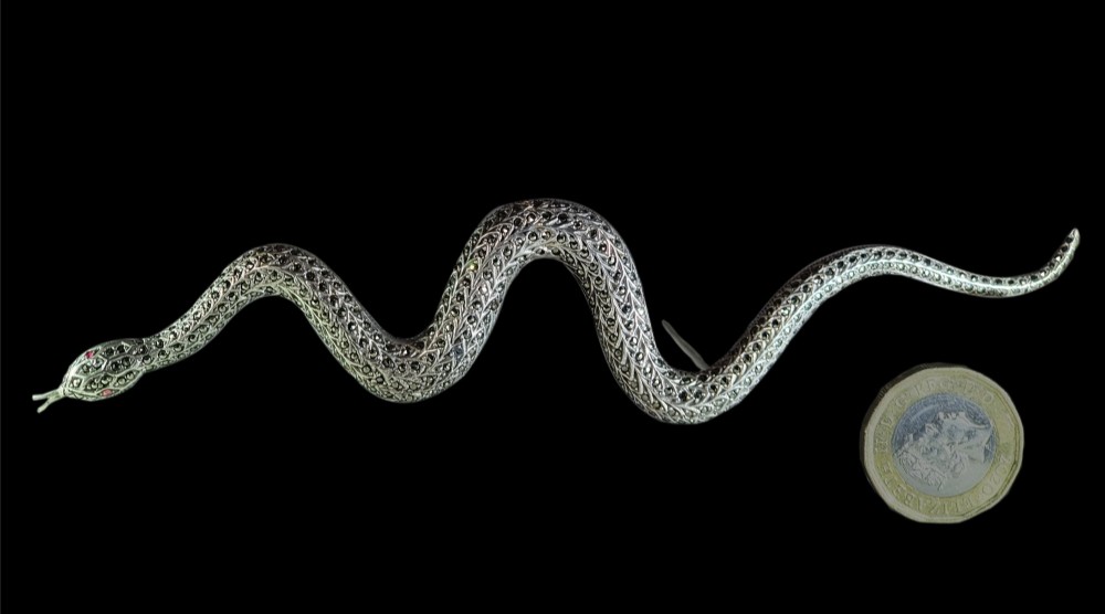 An Art Deco sterling silver brooch formed in the shape of an undulating snake, encrusted with pave-set marcasite stones and detailed with red stone eyes. View II