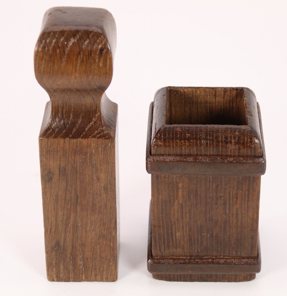 An antique dark oak apothecary crusher set consisting of a square wooden vessel with iron mounts alongside a matching rectangular wooden plunger with a shaped handle.
