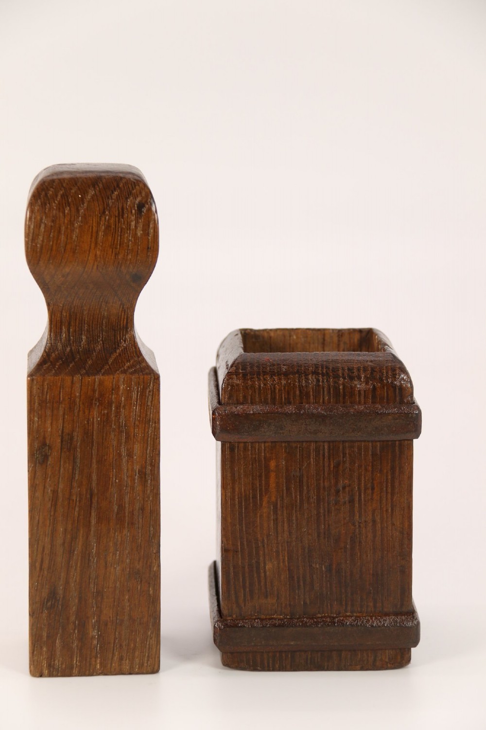 An antique dark oak apothecary crusher set consisting of a square wooden vessel with iron mounts alongside a matching rectangular wooden plunger with a shaped handle. View III