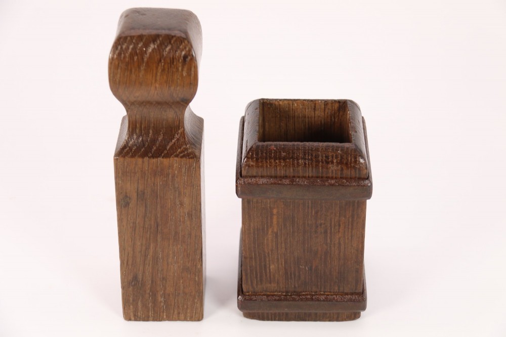 An antique dark oak apothecary crusher set consisting of a square wooden vessel with iron mounts alongside a matching rectangular wooden plunger with a shaped handle. View IV