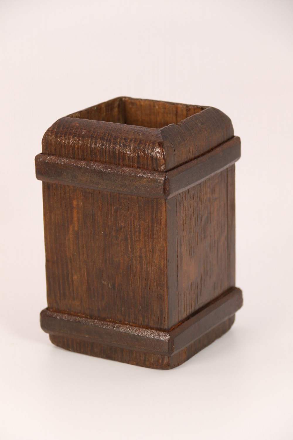An antique dark oak apothecary crusher set consisting of a square wooden vessel with iron mounts alongside a matching rectangular wooden plunger with a shaped handle. View VII