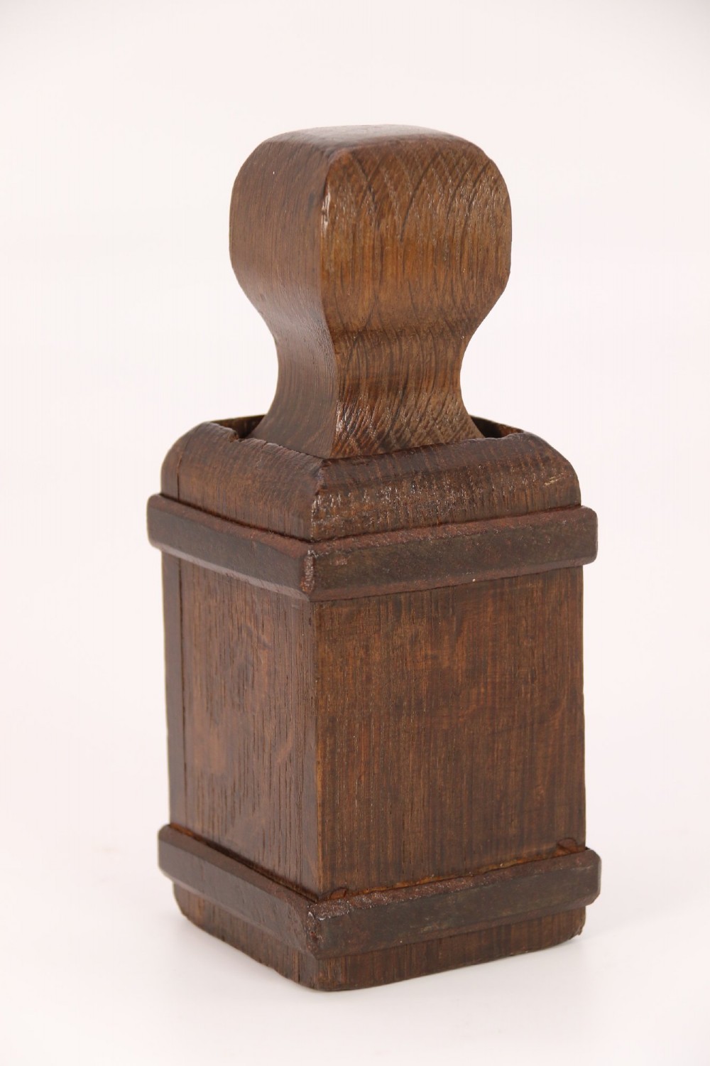 An antique dark oak apothecary crusher set consisting of a square wooden vessel with iron mounts alongside a matching rectangular wooden plunger with a shaped handle. View XIII