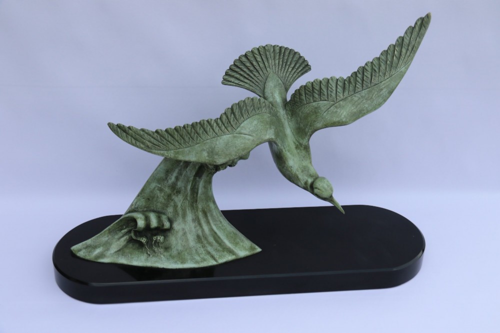 A patinated green bronze sculpture depicting an albatross with extended wings skimming a crested wave, mounted on an oval black marble plinth. View II