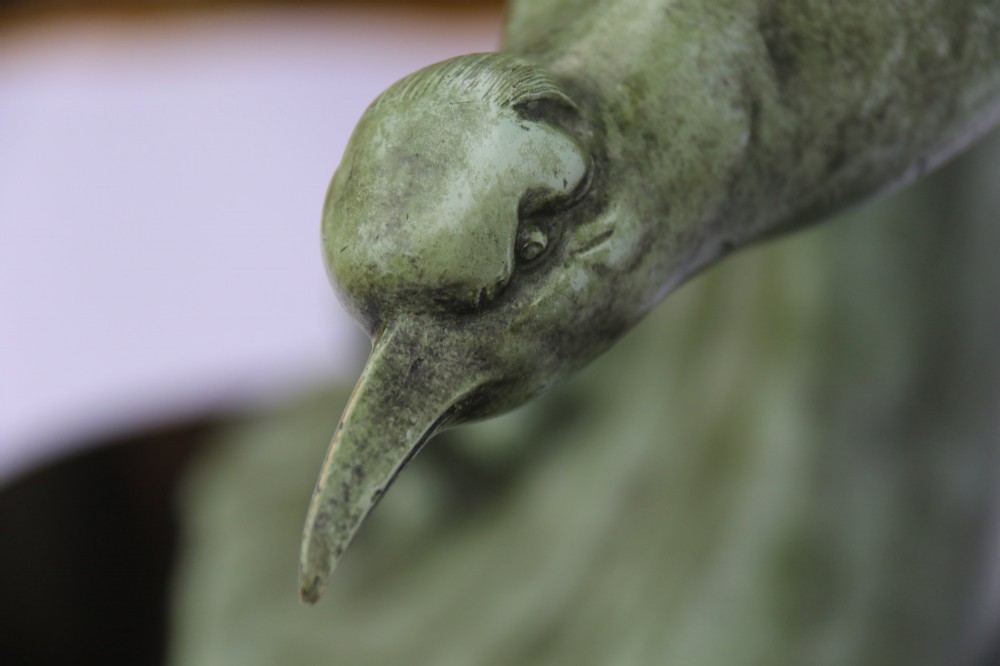 A patinated green bronze sculpture depicting an albatross with extended wings skimming a crested wave, mounted on an oval black marble plinth. View VI