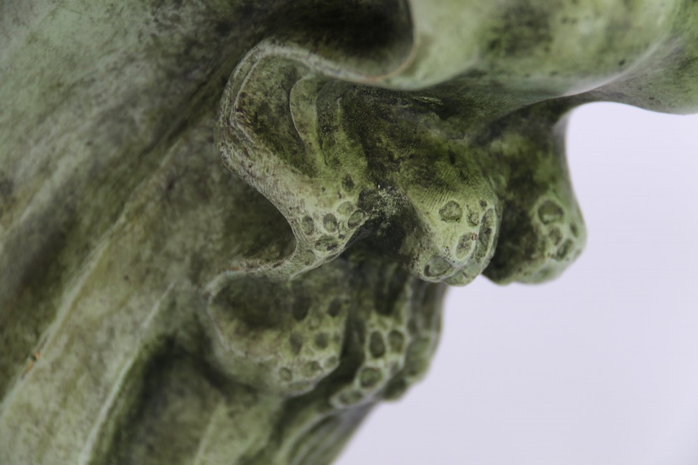 A patinated green bronze sculpture depicting an albatross with extended wings skimming a crested wave, mounted on an oval black marble plinth. View VII