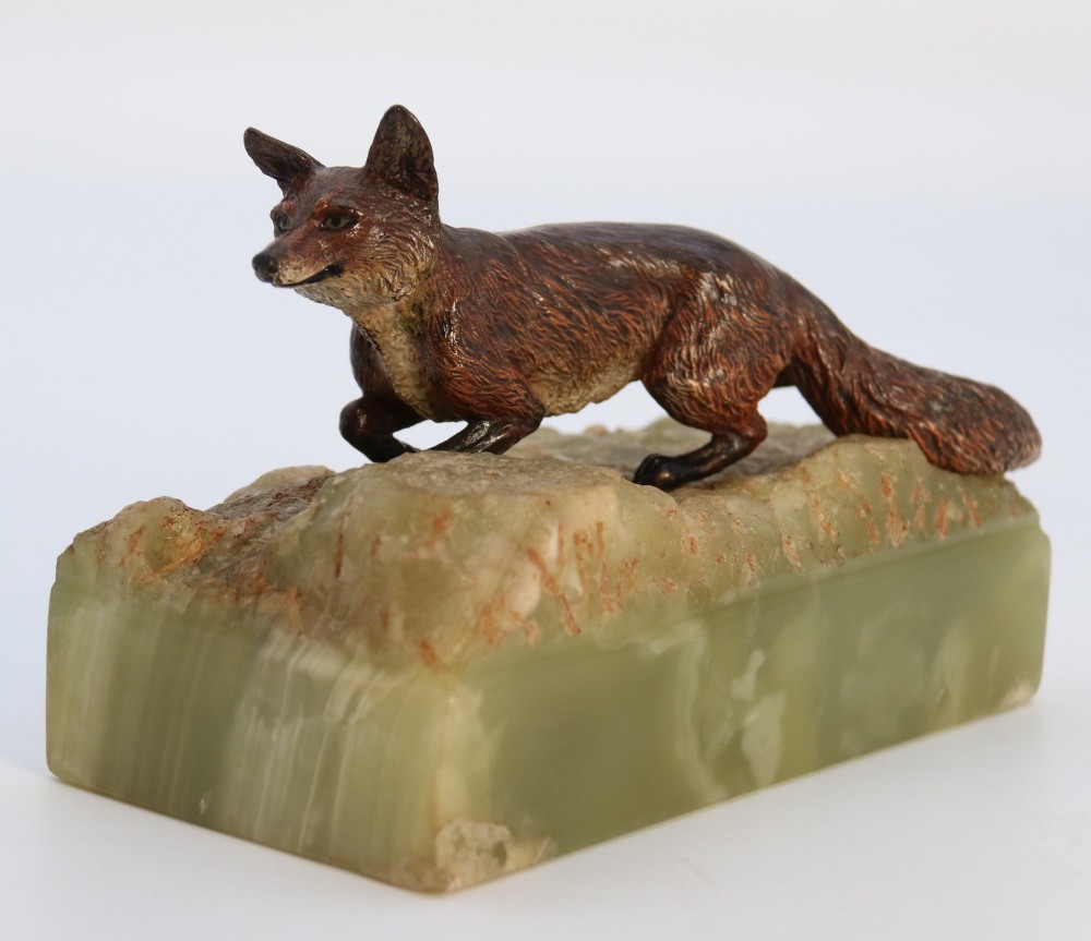 A cold-painted bronze sculpture of a fox in motion, mounted upon a rectangular carved green onyx base.