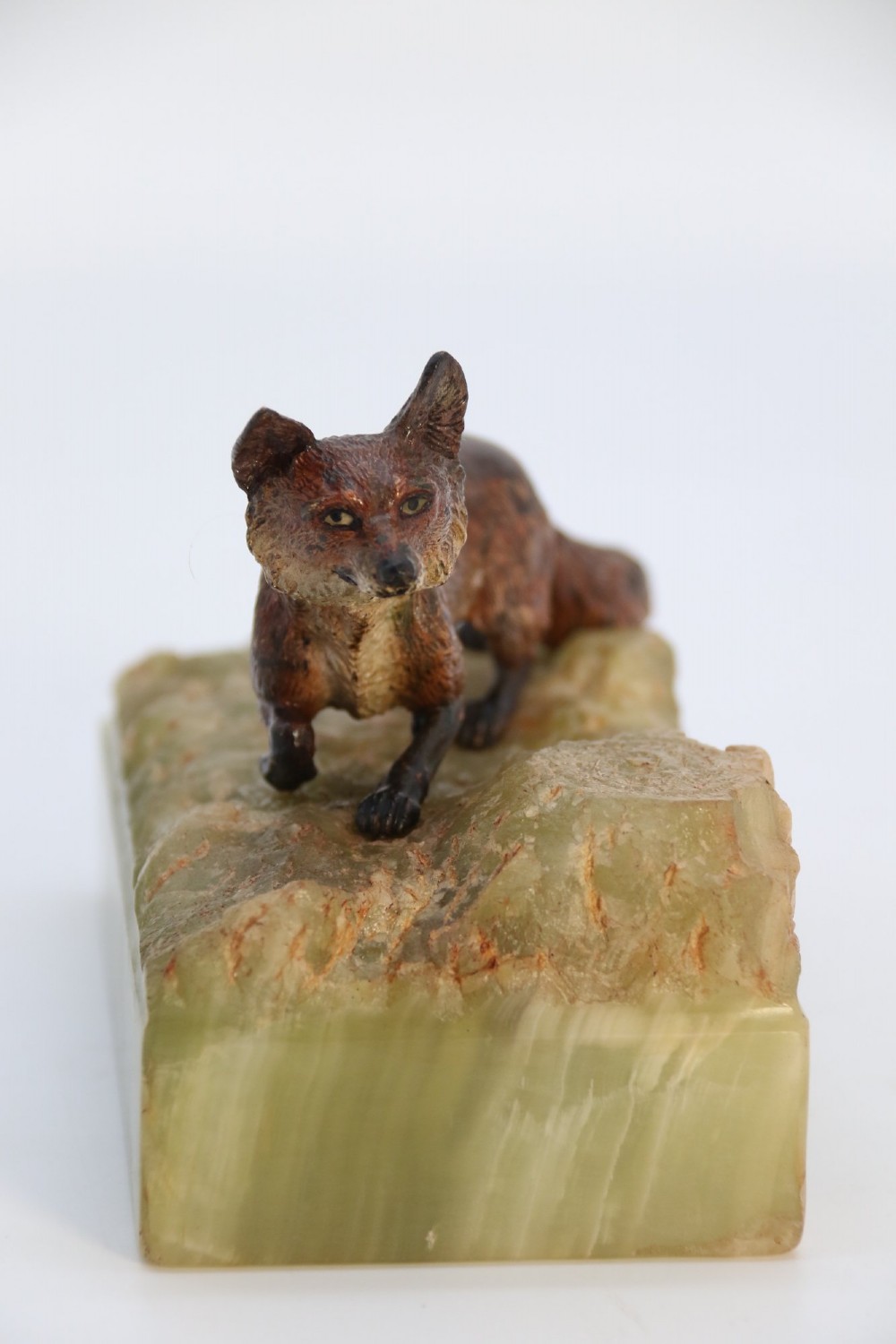 A cold-painted bronze sculpture of a fox in motion, mounted upon a rectangular carved green onyx base. View II