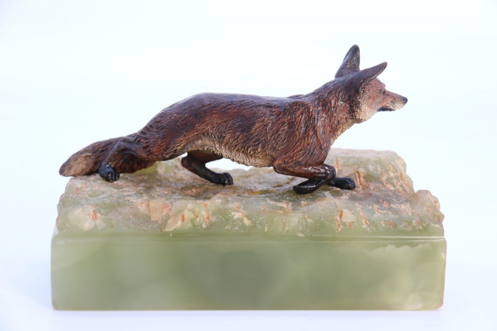 A cold-painted bronze sculpture of a fox in motion, mounted upon a rectangular carved green onyx base. View IV