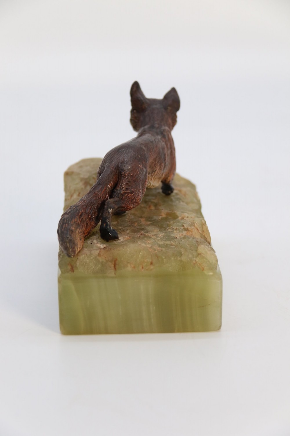 A cold-painted bronze sculpture of a fox in motion, mounted upon a rectangular carved green onyx base. View VI