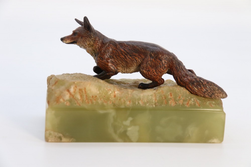A cold-painted bronze sculpture of a fox in motion, mounted upon a rectangular carved green onyx base. View IX