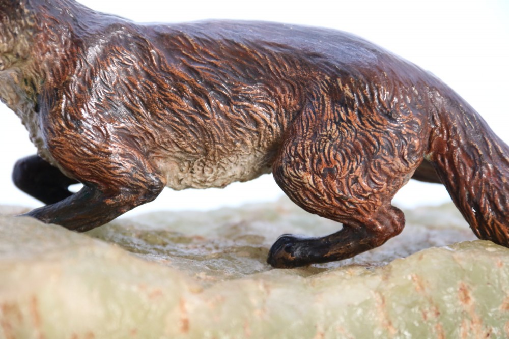 A cold-painted bronze sculpture of a fox in motion, mounted upon a rectangular carved green onyx base. View XIV