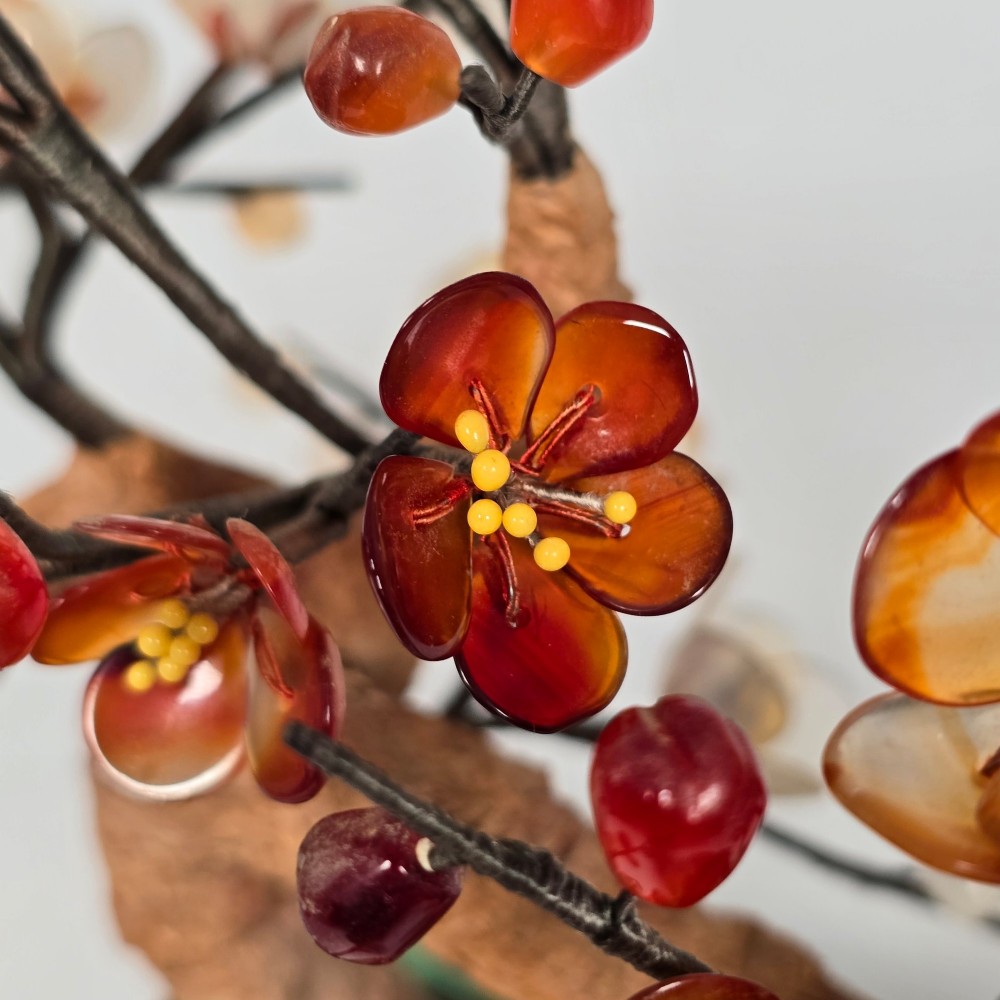 A Chinese decorative bonsai tree featuring carved amber-coloured hardstone plum blossoms on wired branches set inside a turquoise floral cloisonne planter. View VI
