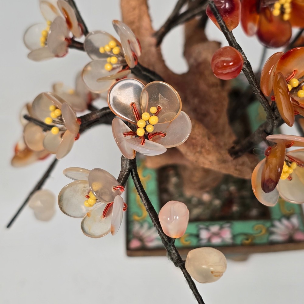 A Chinese decorative bonsai tree featuring carved amber-coloured hardstone plum blossoms on wired branches set inside a turquoise floral cloisonne planter. View IX