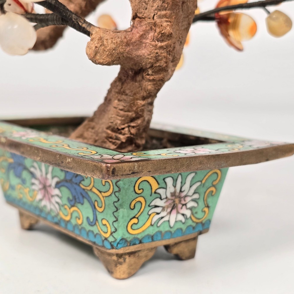 A Chinese decorative bonsai tree featuring carved amber-coloured hardstone plum blossoms on wired branches set inside a turquoise floral cloisonne planter. View XI