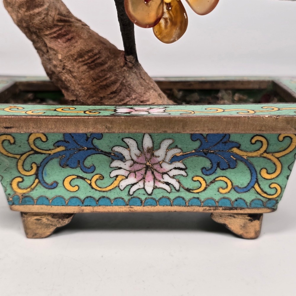 A Chinese decorative bonsai tree featuring carved amber-coloured hardstone plum blossoms on wired branches set inside a turquoise floral cloisonne planter. View XIII