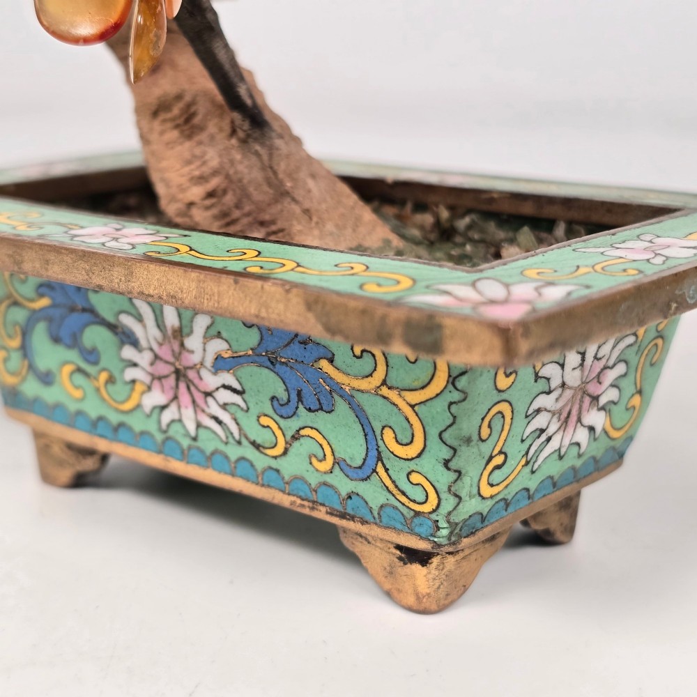 A Chinese decorative bonsai tree featuring carved amber-coloured hardstone plum blossoms on wired branches set inside a turquoise floral cloisonne planter. View XIV