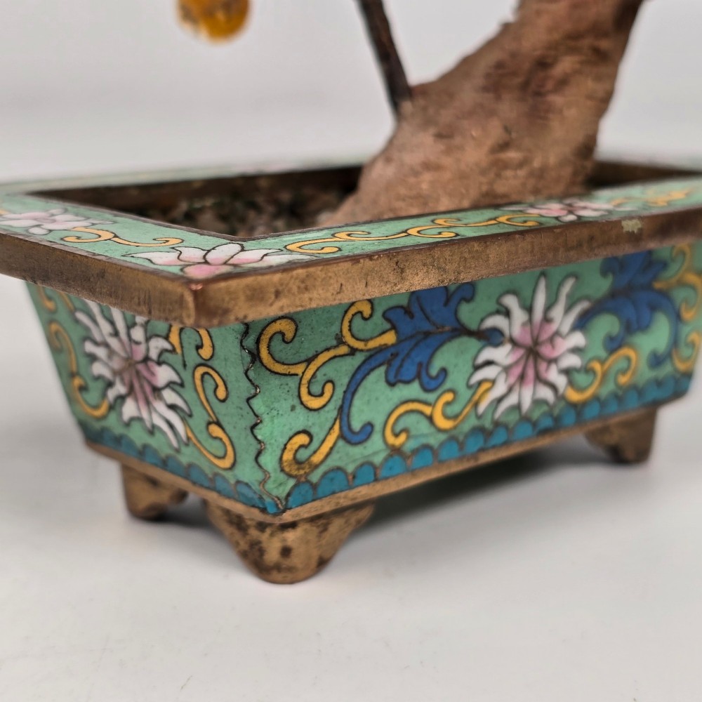 A Chinese decorative bonsai tree featuring carved amber-coloured hardstone plum blossoms on wired branches set inside a turquoise floral cloisonne planter. View XV