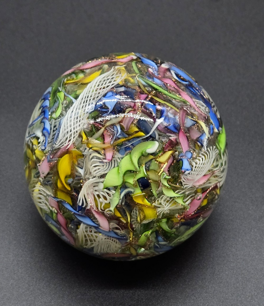 A clear spherical glass paperweight filled with an intricate mix of colourful cane fragments, white filigree ribbons, and glittering gold aventurine flecks. View VIII