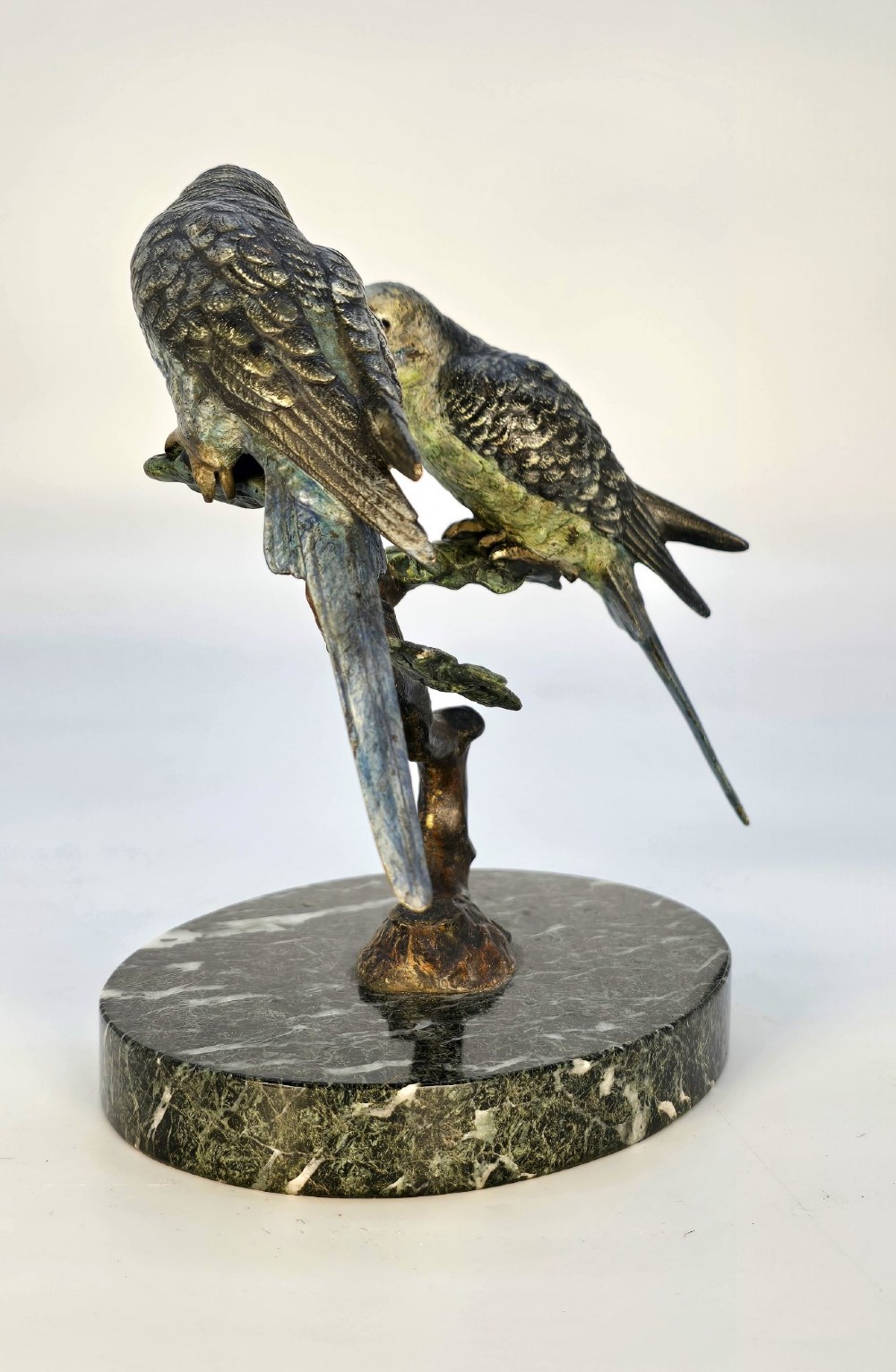 A cold-painted bronze sculpture featuring two budgerigars perched on a branch mounted upon a round green marble base. View V