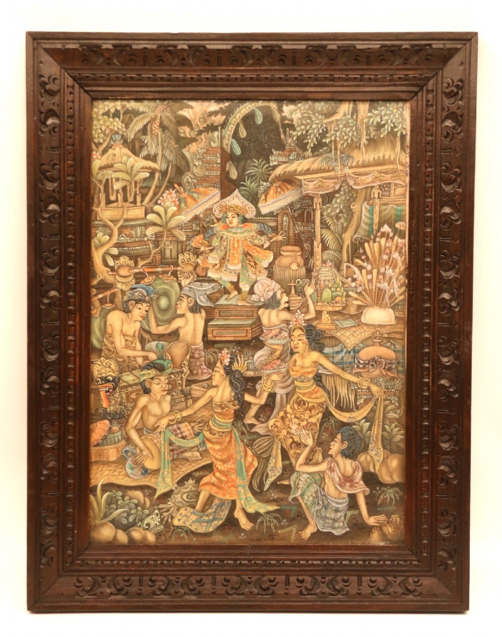 A detailed Balinese painting depicting figures dancing and playing gamelan instruments within a lush landscape, set inside a carved dark wood frame.