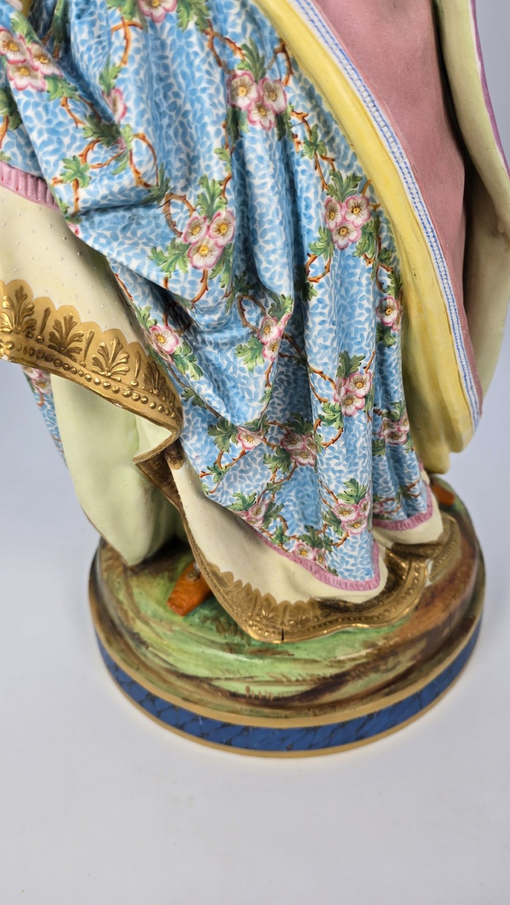A pair of large hand-painted French porcelain statuettes depicting an 18th-century man and woman in elaborate court attire standing on decorated round pedestals. View VIII