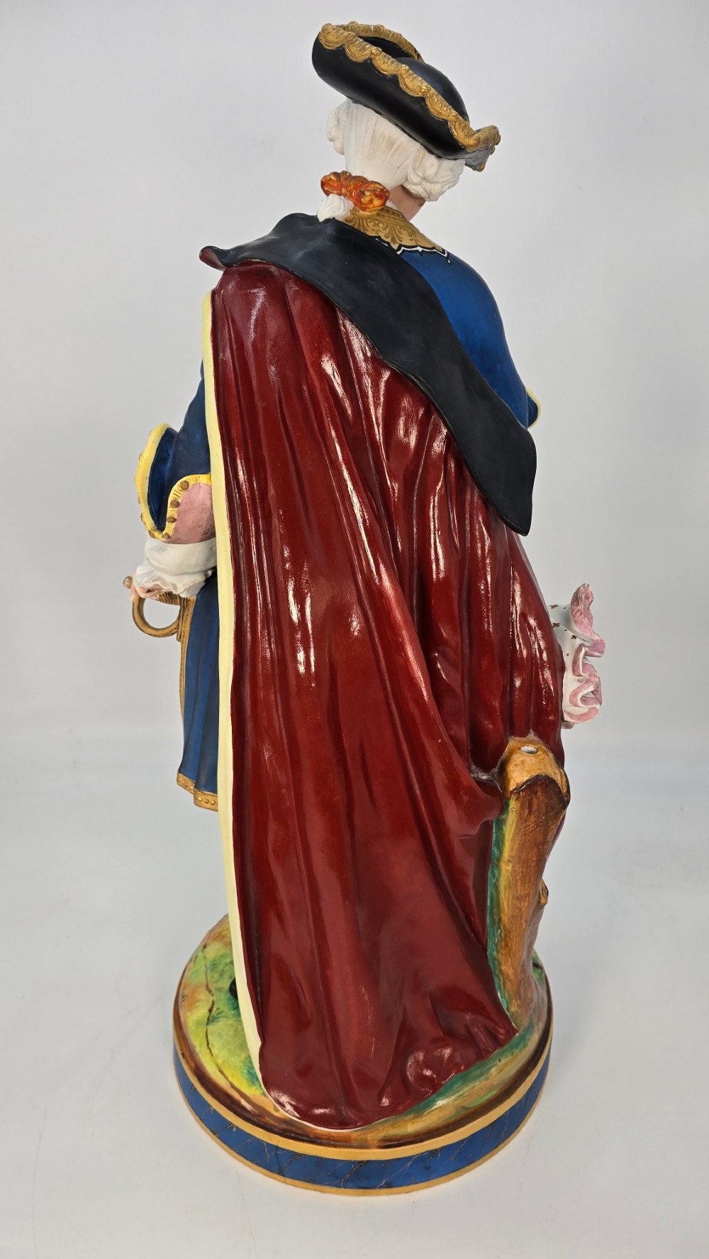 A pair of large hand-painted French porcelain statuettes depicting an 18th-century man and woman in elaborate court attire standing on decorated round pedestals. View XII