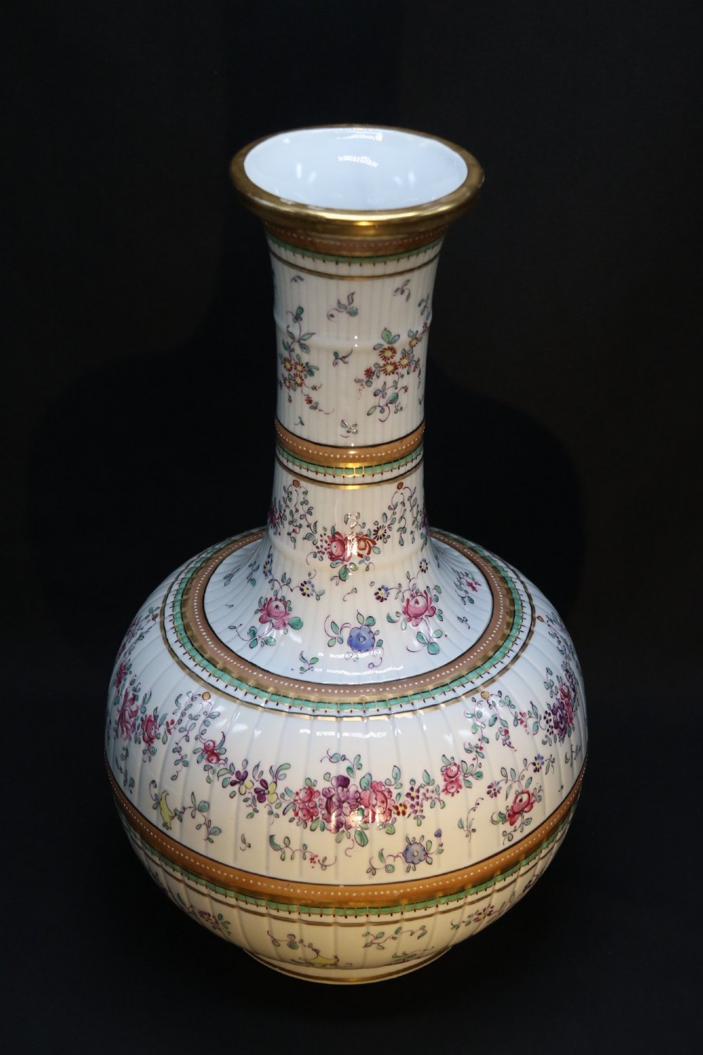A bulbous hand-painted white porcelain vase with vertical fluting, decorated with floral sprigs and gold gilded borders.