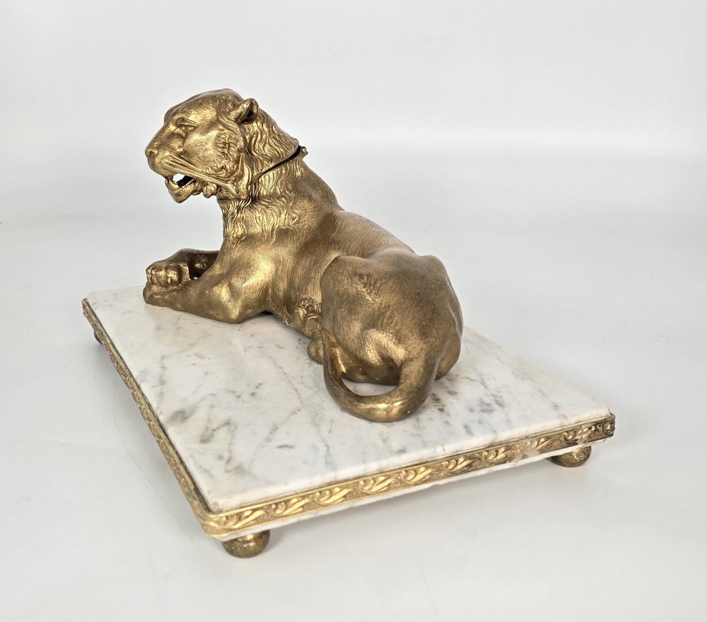 A French gilt bronze figure of a recumbent lion mounted on a rectangular white marble plinth with gilt borders and ball feet. View IV