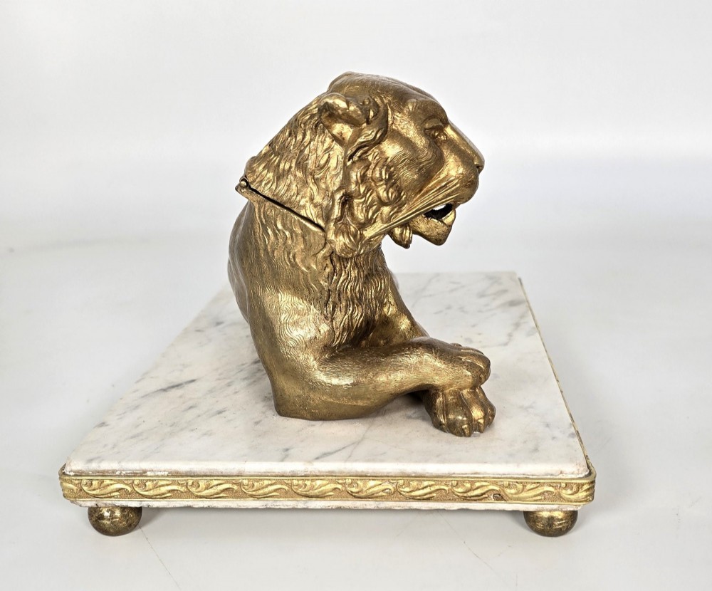 A French gilt bronze figure of a recumbent lion mounted on a rectangular white marble plinth with gilt borders and ball feet. View VI