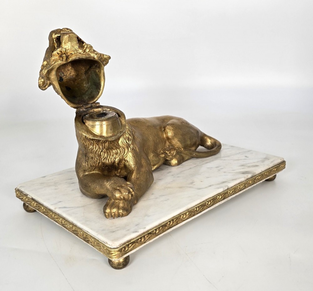 A French gilt bronze figure of a recumbent lion mounted on a rectangular white marble plinth with gilt borders and ball feet. View VII