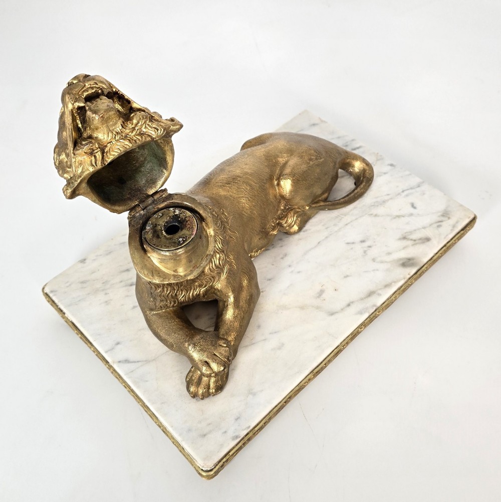 A French gilt bronze figure of a recumbent lion mounted on a rectangular white marble plinth with gilt borders and ball feet. View VIII