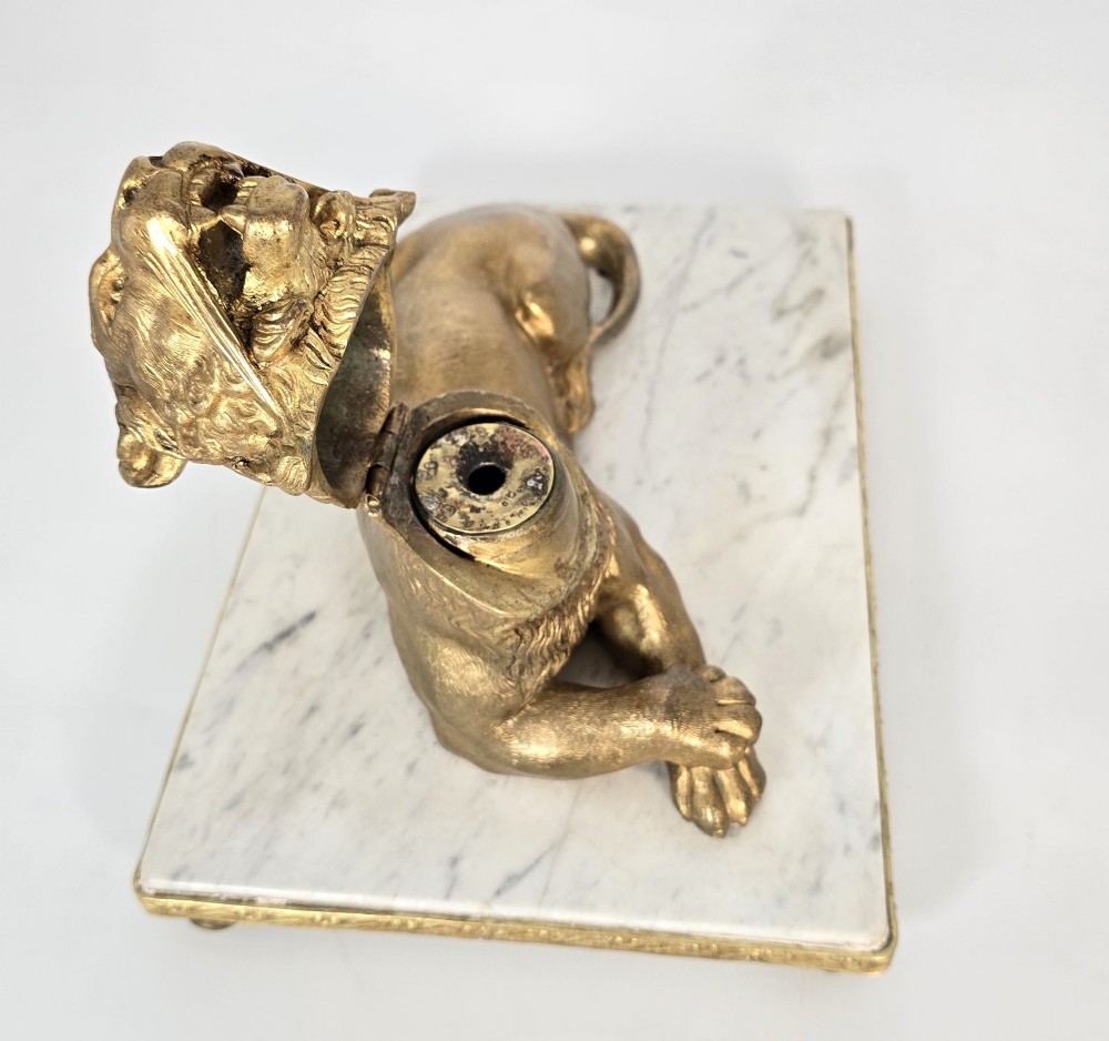 A French gilt bronze figure of a recumbent lion mounted on a rectangular white marble plinth with gilt borders and ball feet. View IX