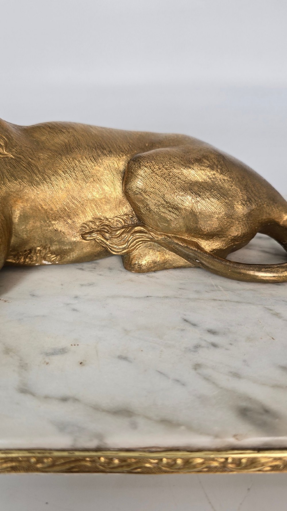 A French gilt bronze figure of a recumbent lion mounted on a rectangular white marble plinth with gilt borders and ball feet. View XI