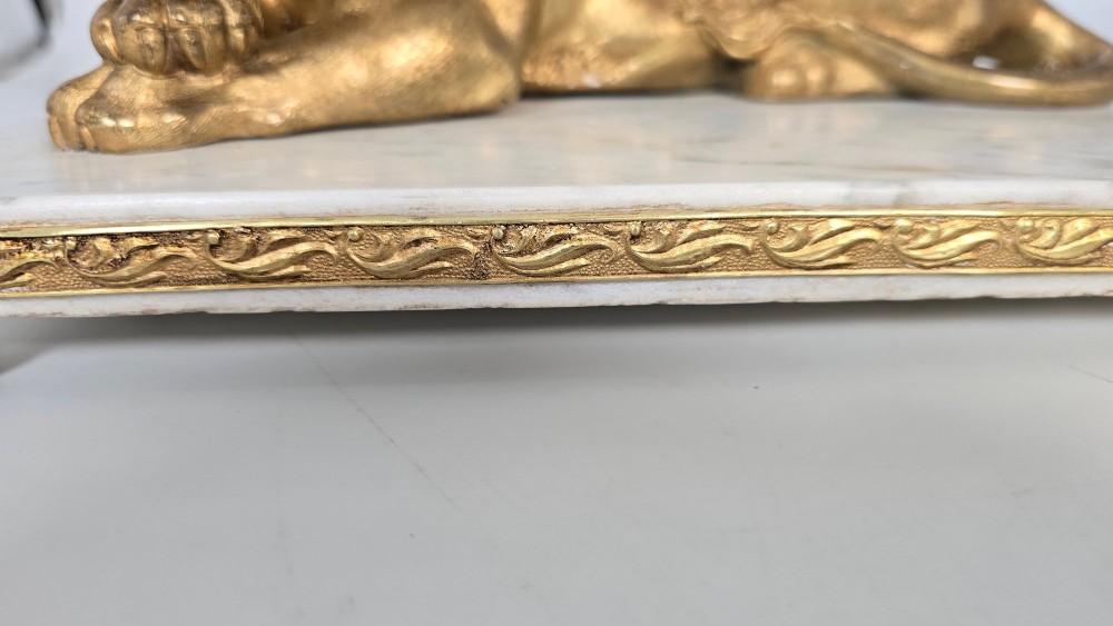 A French gilt bronze figure of a recumbent lion mounted on a rectangular white marble plinth with gilt borders and ball feet. View XII